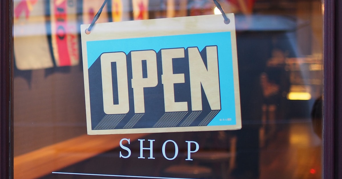 US business owner standing outside their Main Street storefront, American commercial context