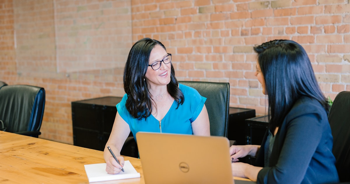 Two professionals comparing financing options at a conference table, decision moment
