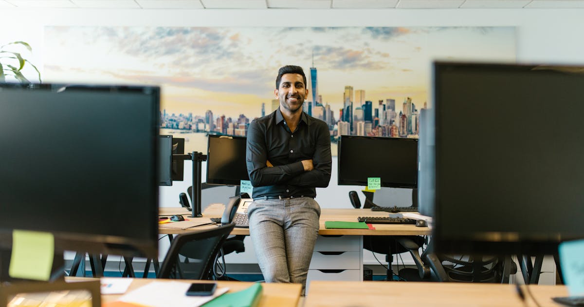 Business owner in black shirt seated at modern desk with cityscape backdrop, reviewing strategy